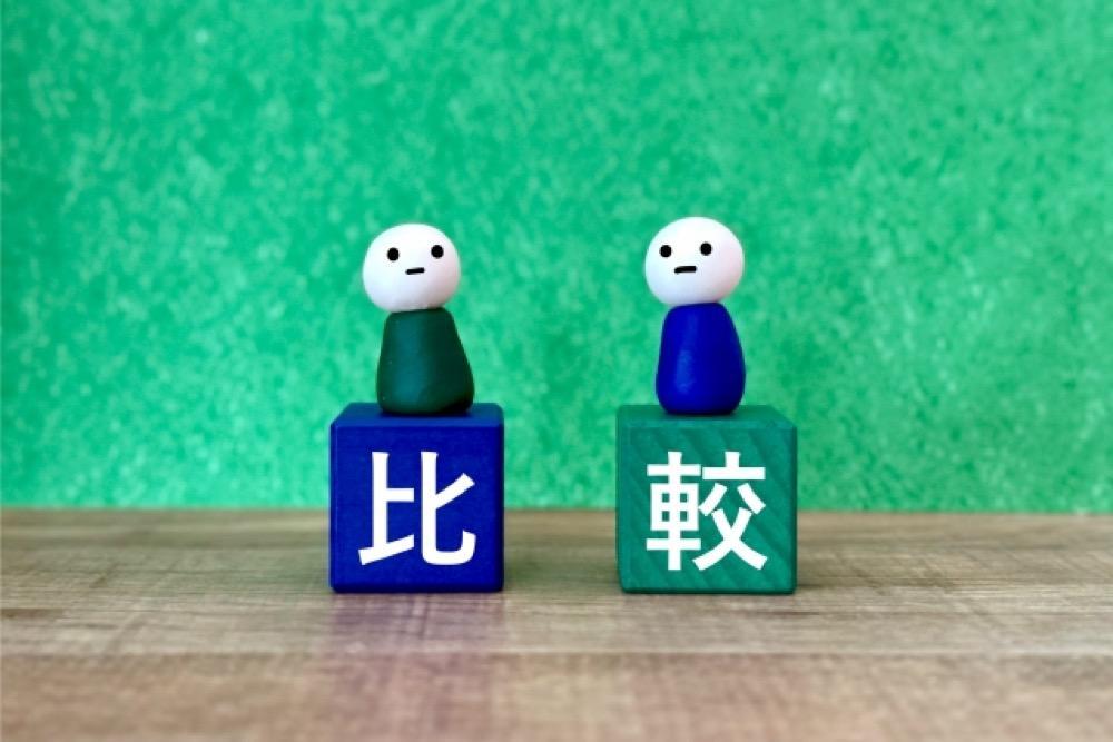 緑色の背景に「比較」と書かれた積み木の上に人形が座っている