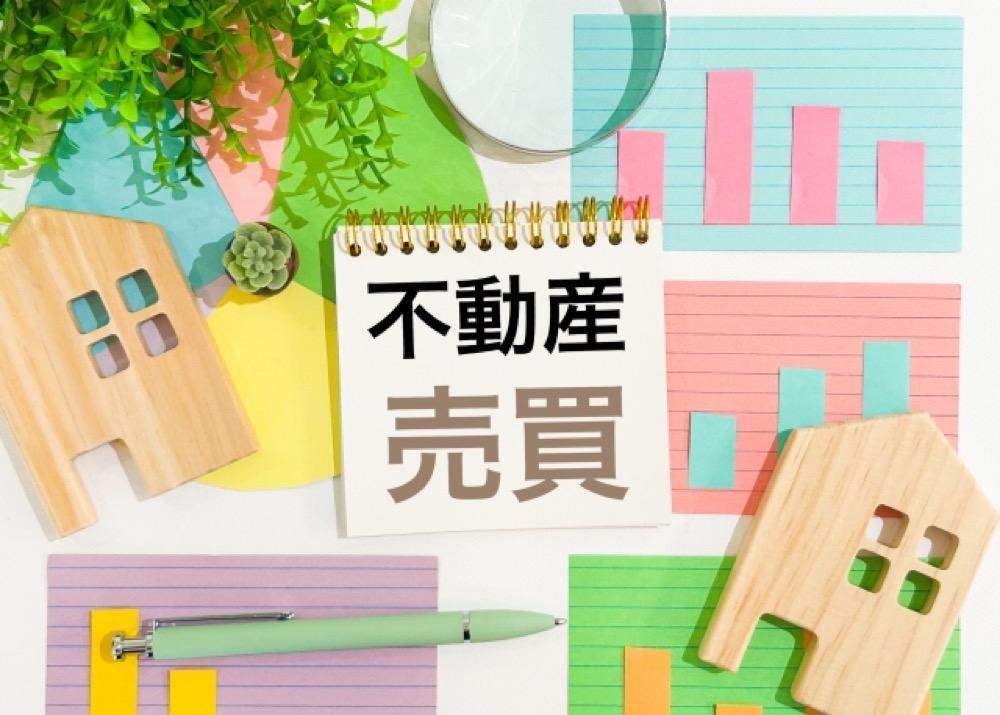 不動産売買に関する資料やグラフ、木製の家が並ぶイメージ