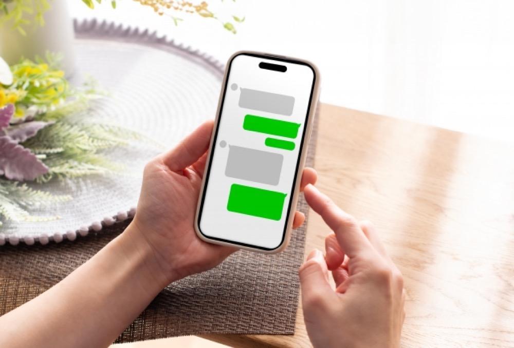 スマートフォンでチャットアプリを操作している人の手元