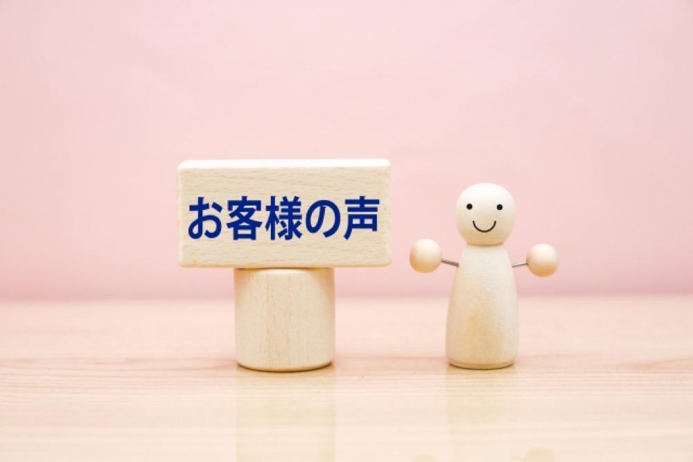 お客様の声を表すプレートと笑顔の木製人形