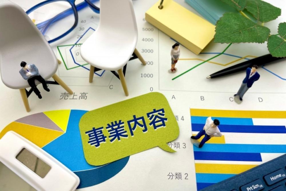 事業内容を示す図表とミニチュアのビジネスパーソンたち