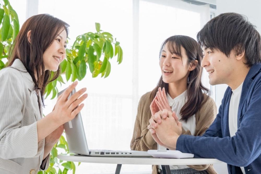 「仲介手数料」と書かれた木製ブロックと住宅模型、観葉植物が並ぶテーブル